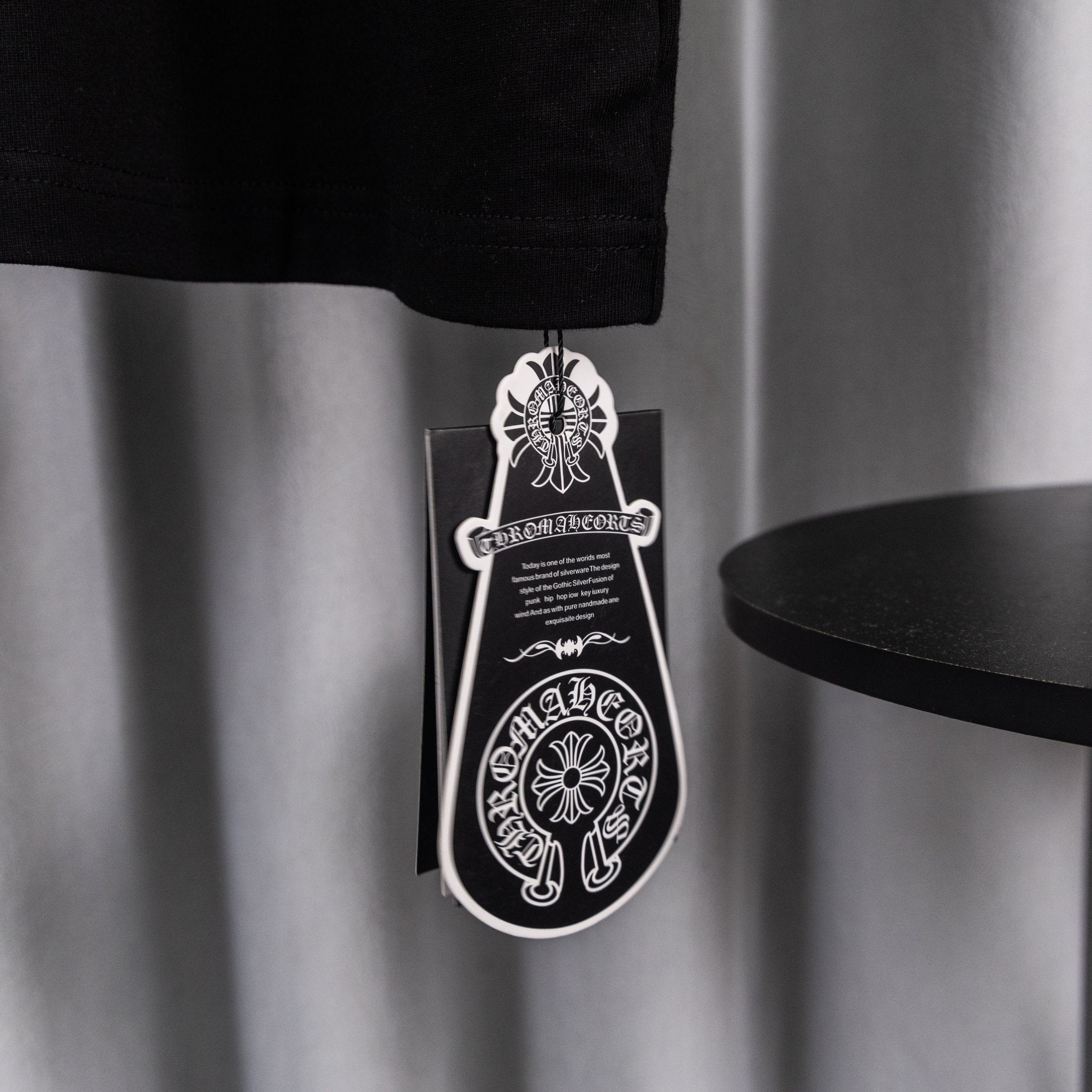 Black T-shirt with hanging product tag and chain near hem