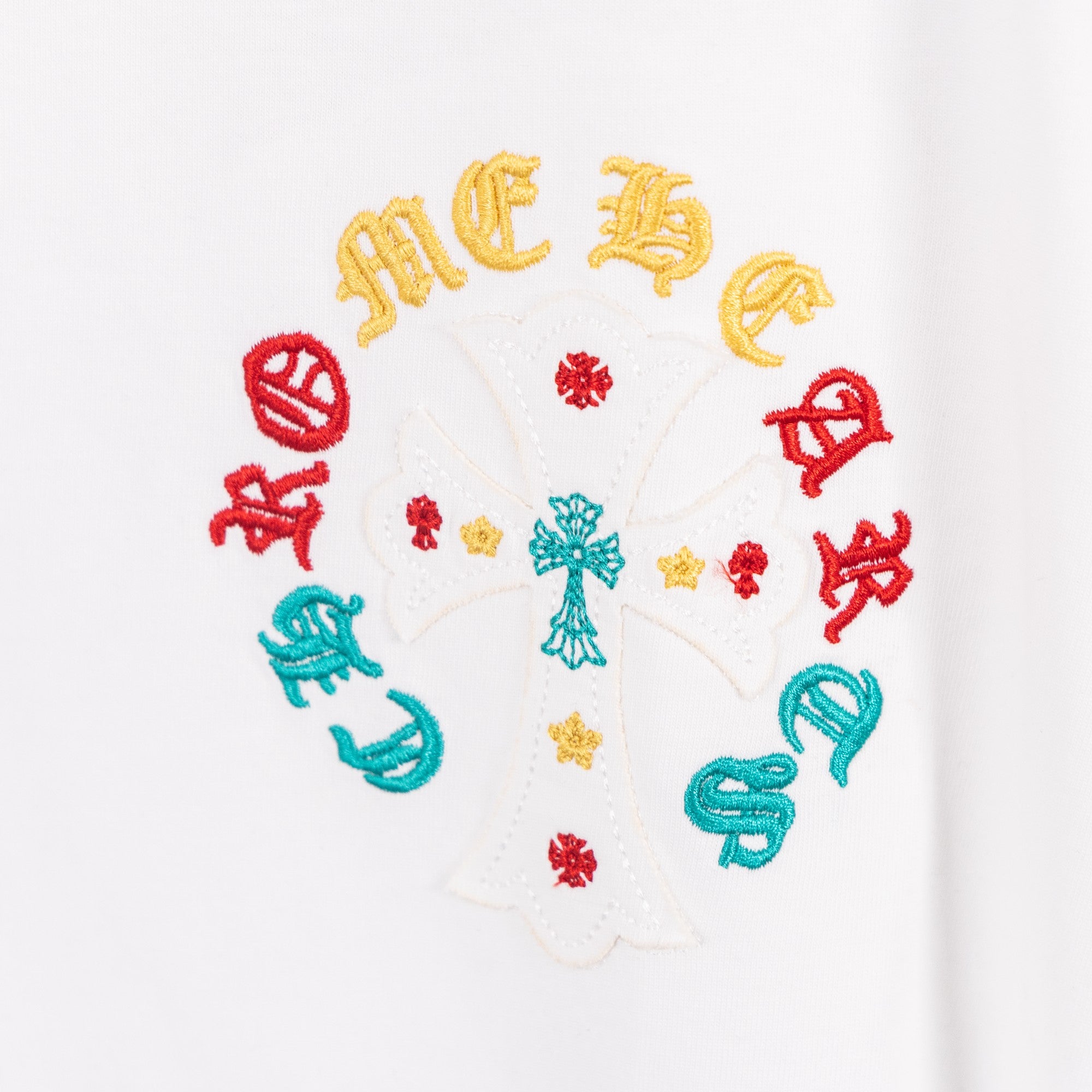 White T-shirt circular multicolor graphic with a central cross and colored accents.