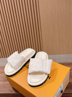 White Louis Vuitton monogram slide sandals on orange box, front view