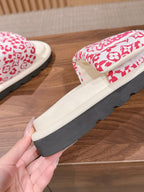 Side view of pink floral logo-pattern slide sandals with thick dark rubber sole