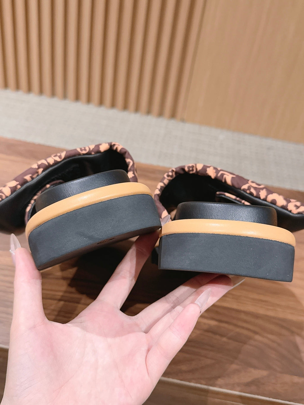 Close-up of slide sandal outsoles and footbeds with dark platform and light trim.