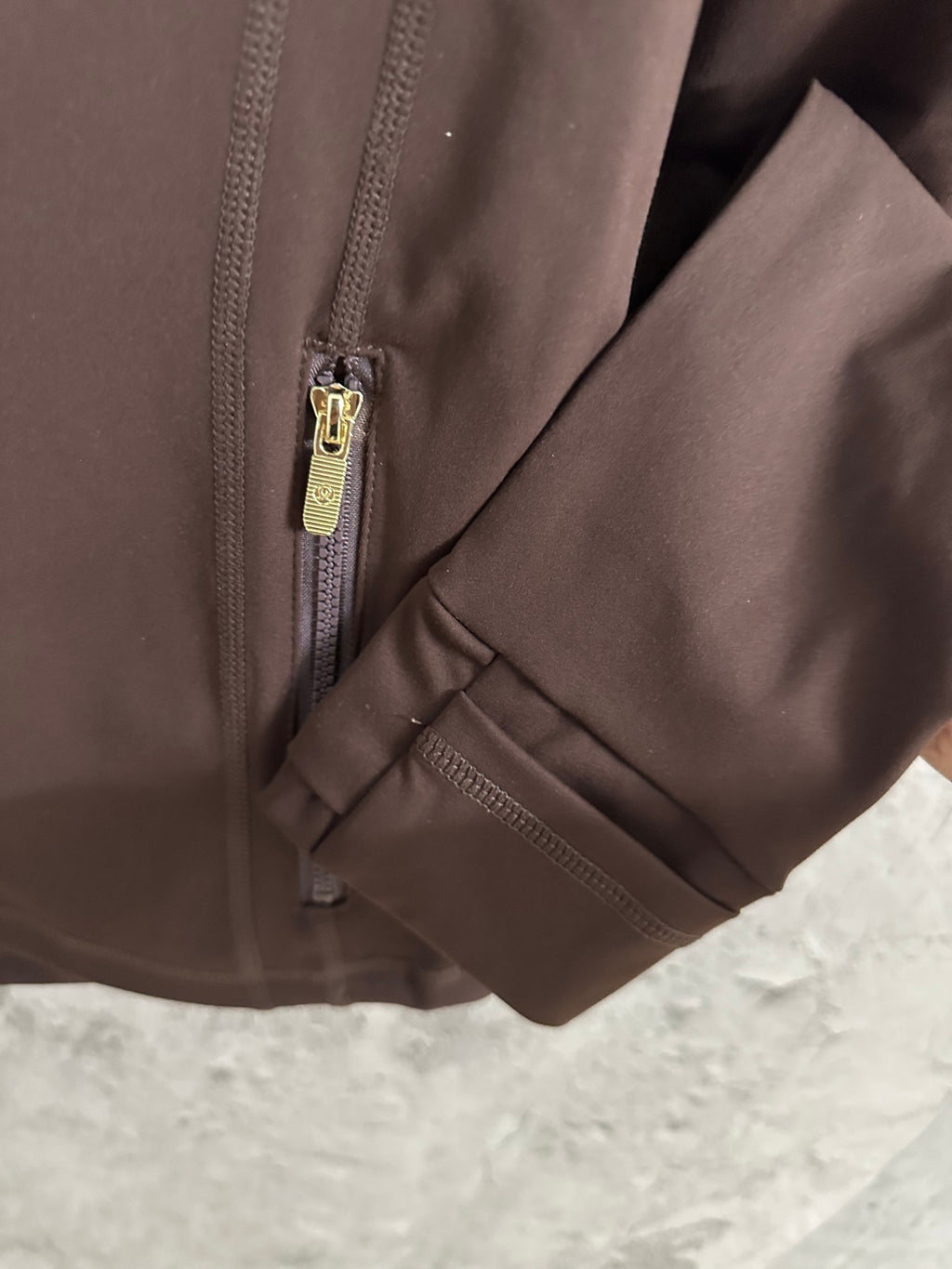 Brown jacket sleeve cuff with small zipper detail and side pocket zipper