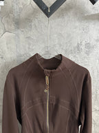 Brown stand-collar jacket close-up with front zipper and stitched shoulder panels