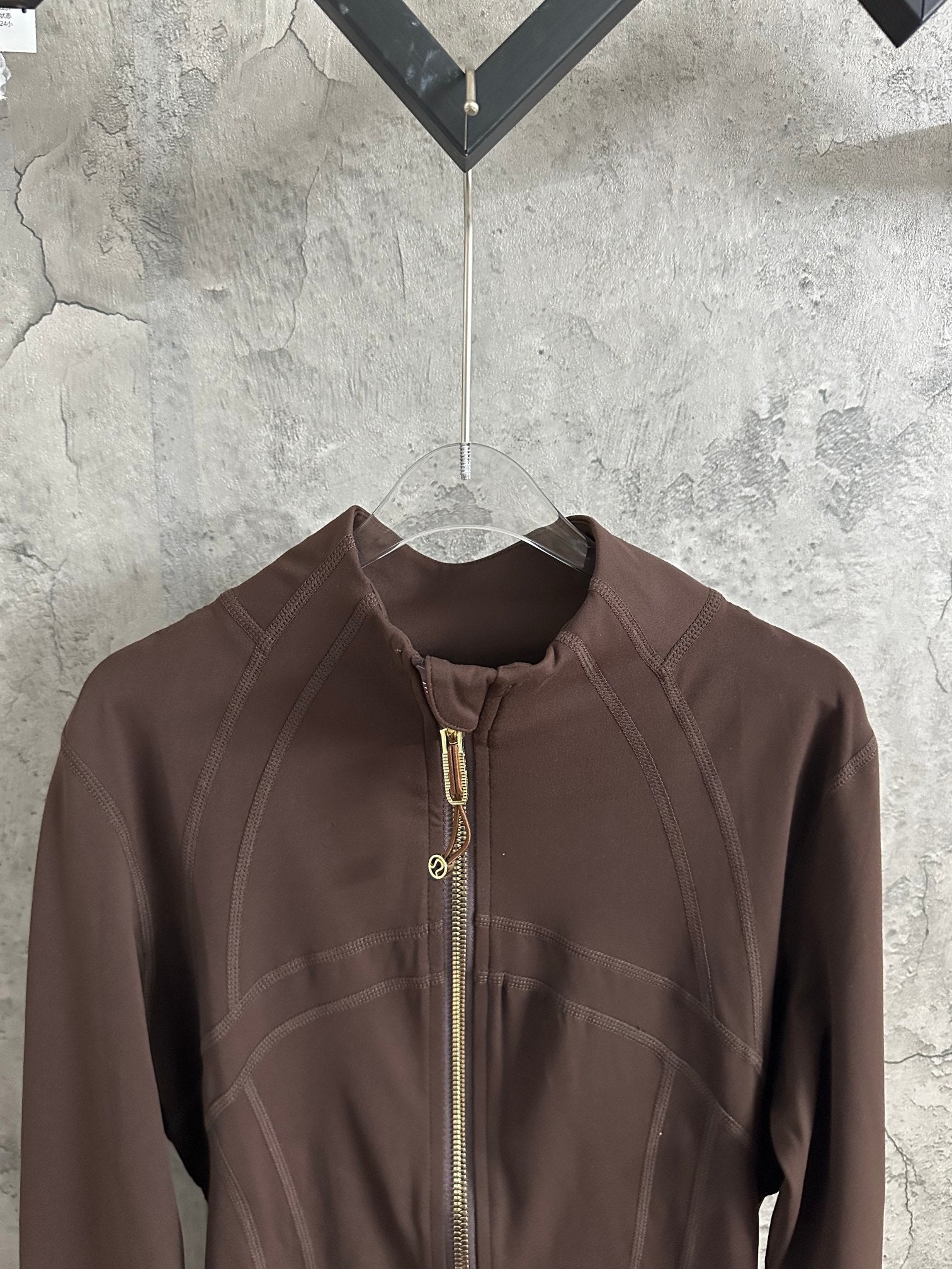 Brown stand-collar jacket close-up with front zipper and stitched shoulder panels