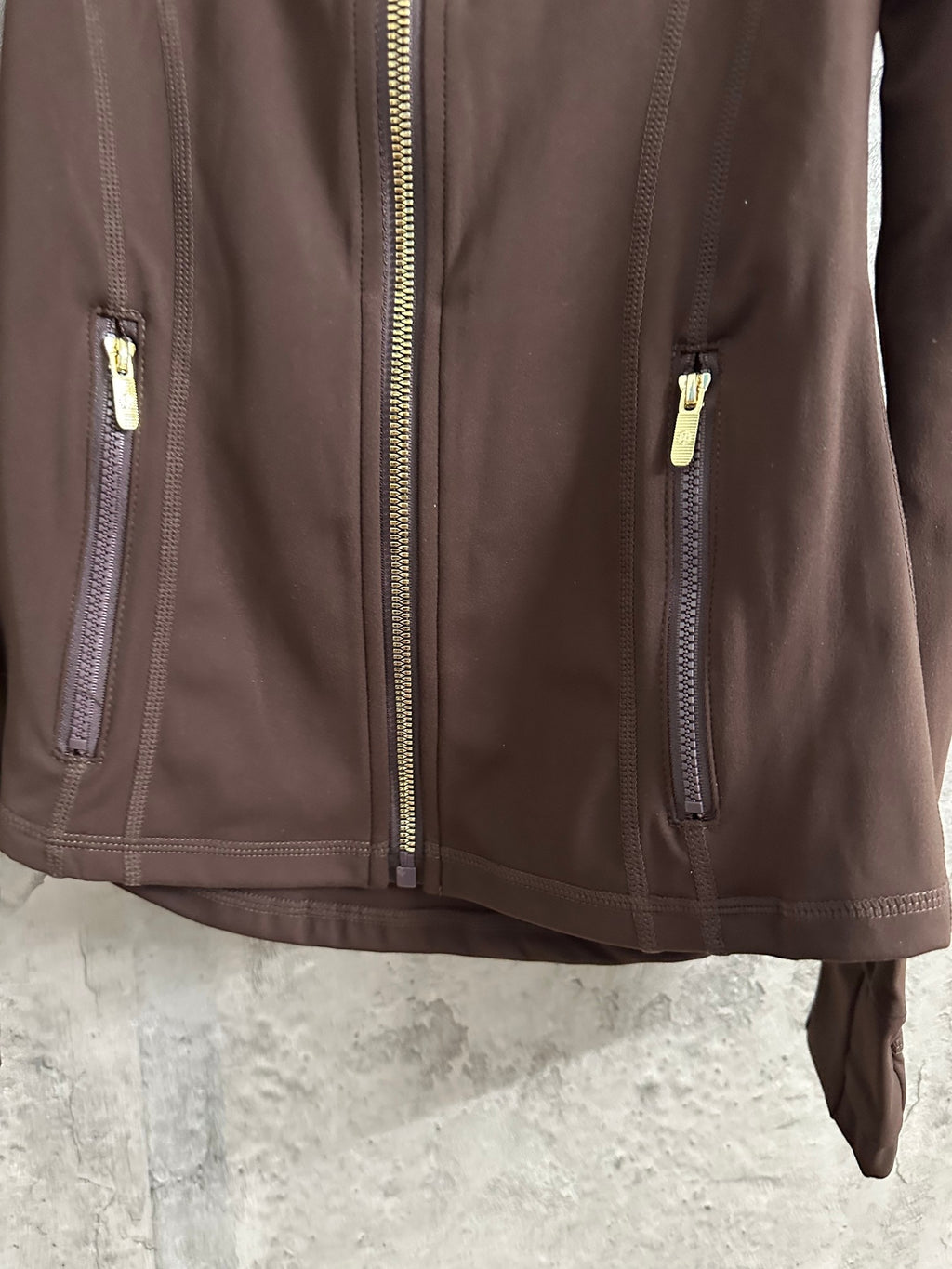 Brown jacket front with gold-tone zip pull and two zip pockets at sides
