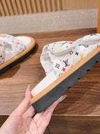 Louis Vuitton slide sandals close-up, white monogram straps with dark sole and tan base