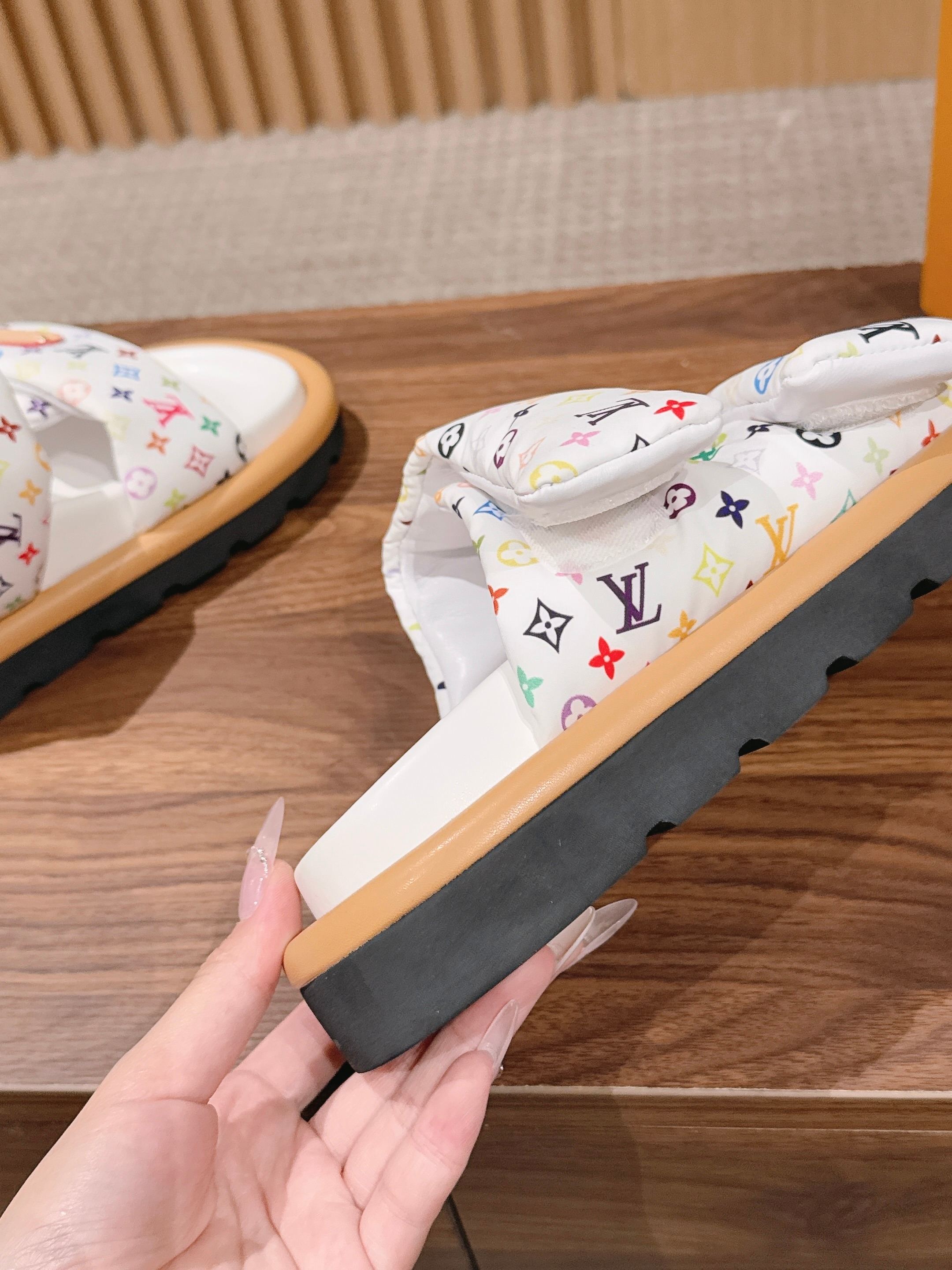Louis Vuitton slide sandals close-up, white monogram straps with dark sole and tan base