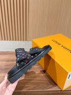 Slide sandals with multicolor logo straps and black rubber sole, side view
