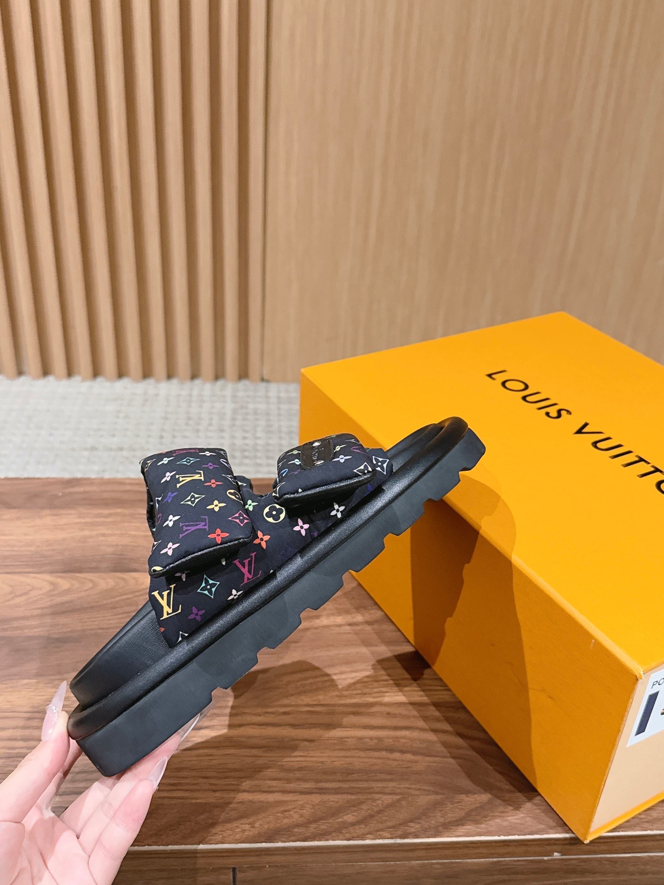 Slide sandals with multicolor logo straps and black rubber sole, side view