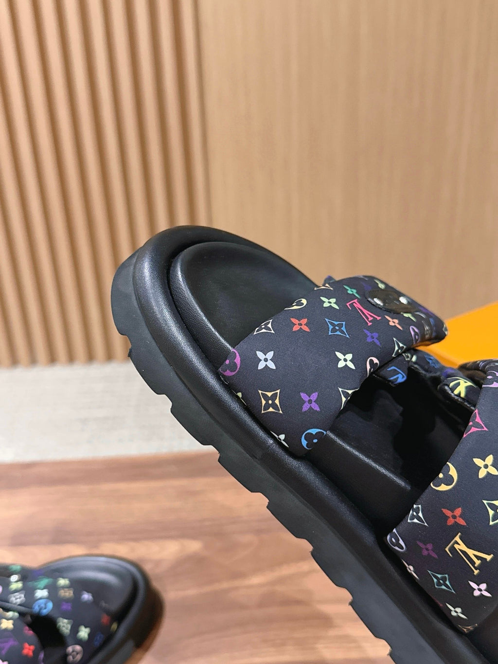 Slide sandals close-up: black sole with multicolor logo strap detail