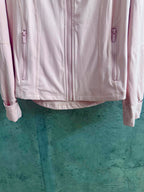 Light pink zip-up jacket with two vertical zippers at the waist and cuffs