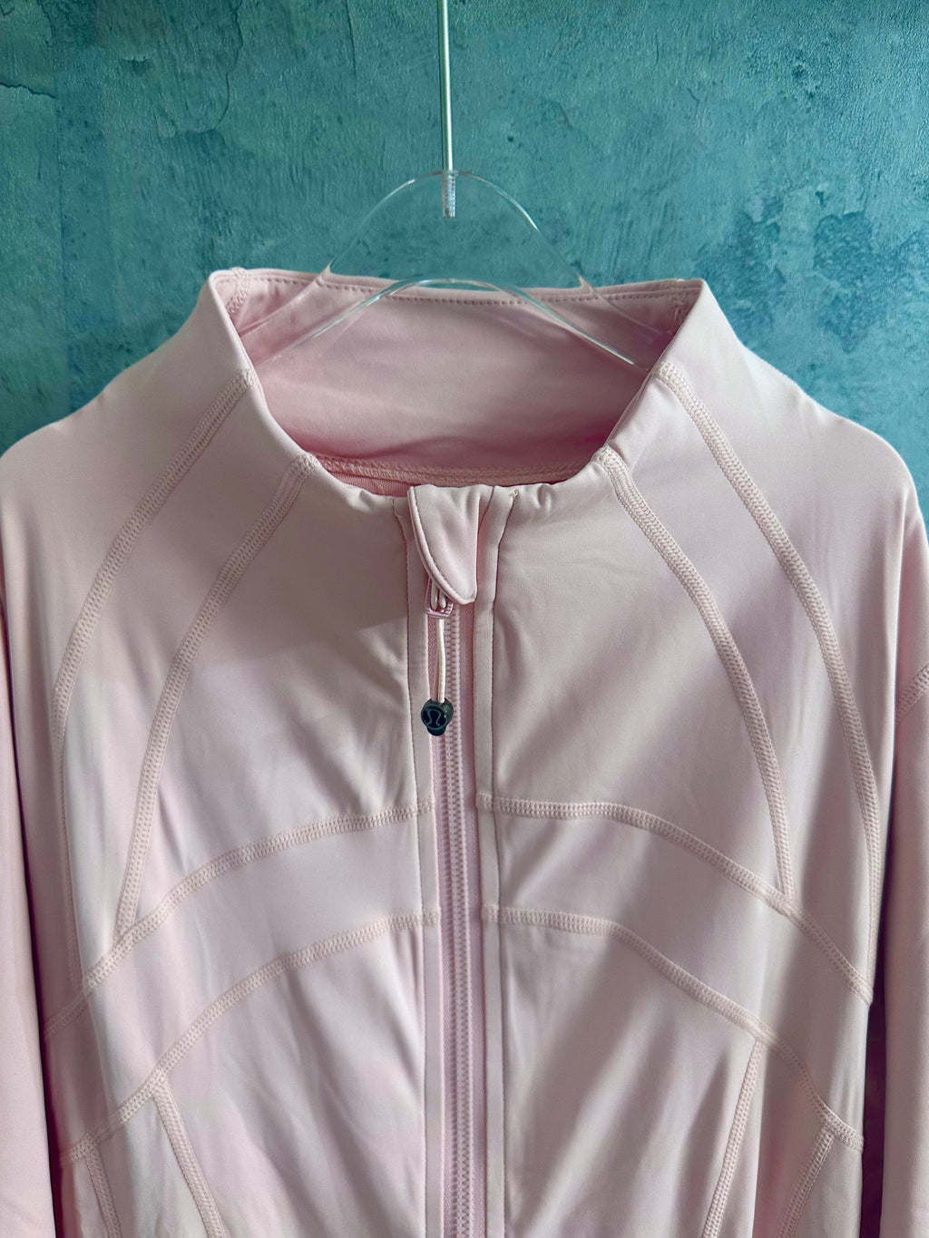 Light pink zip-up jacket with stand collar, zipper, and small chest emblem