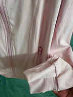 Light pink zip-up jacket cuff with zipper pull and stitched detail