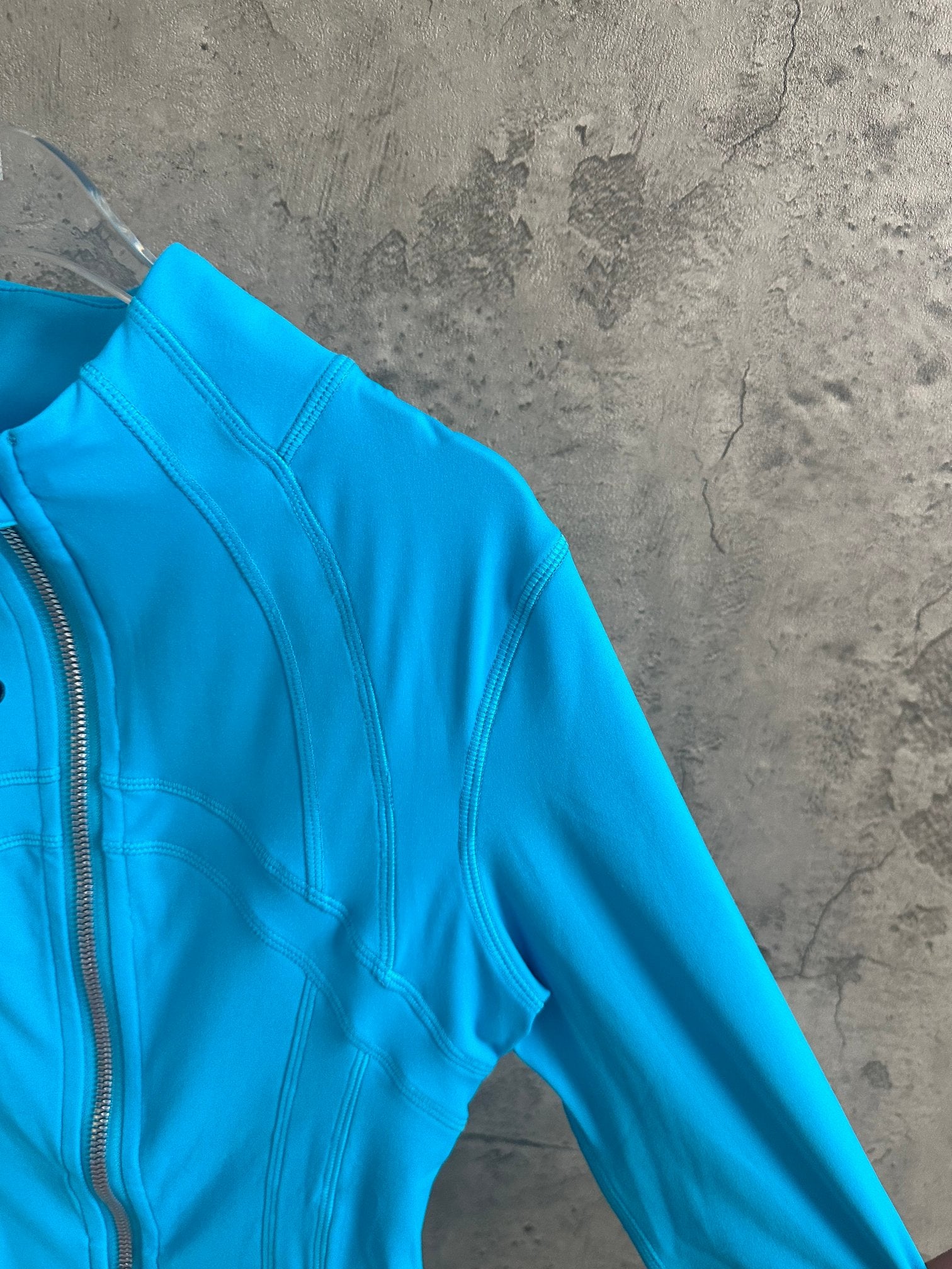 Light blue jacket sleeve with stitched panels and zipper placket edge