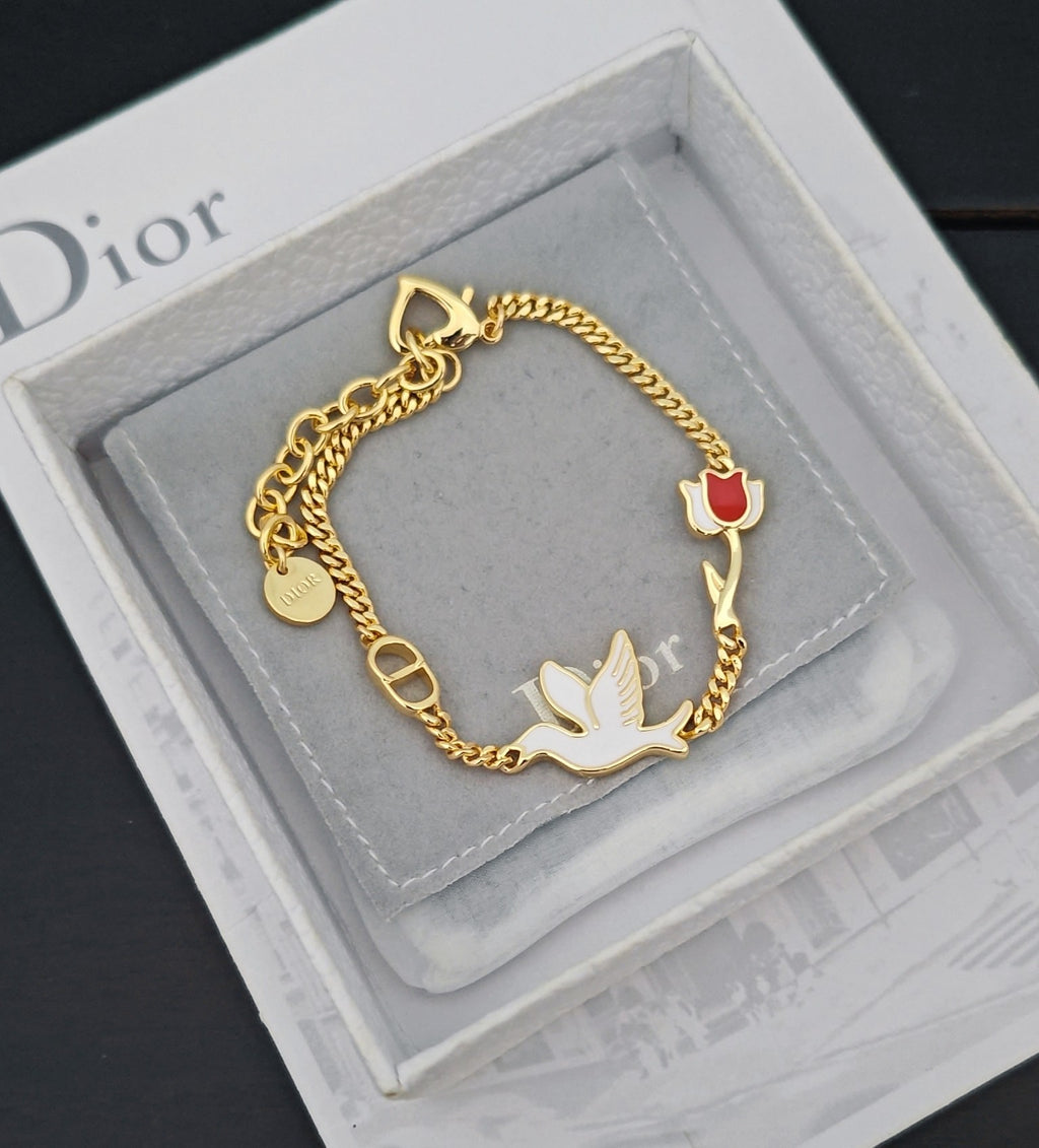 Gold-tone charm bracelet with bird charms and red enamel heart on cushion