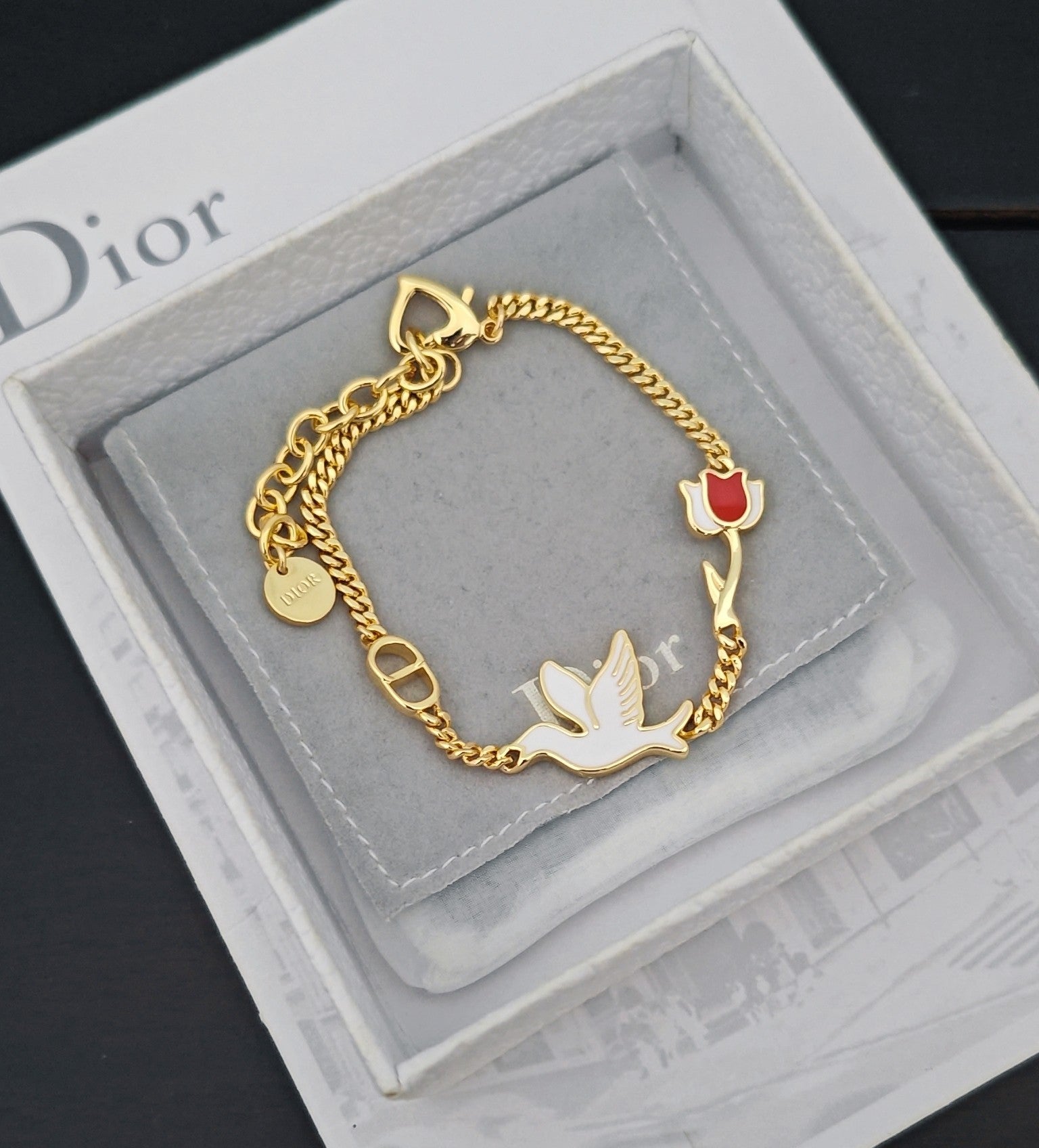 Gold-tone charm bracelet with bird charms and red enamel heart on cushion