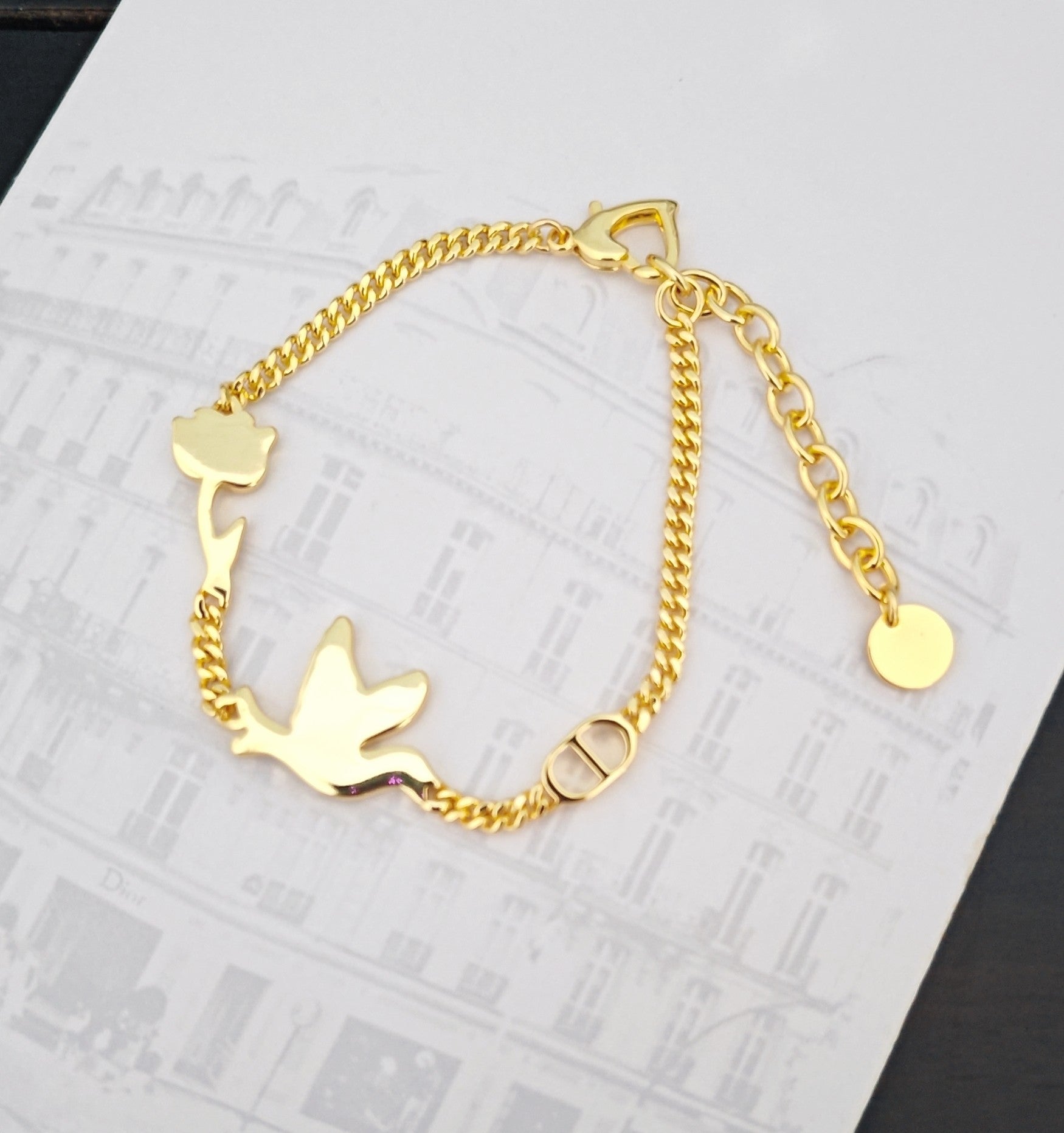 Gold-tone charm bracelet with bird motifs, chain links and clasp detail