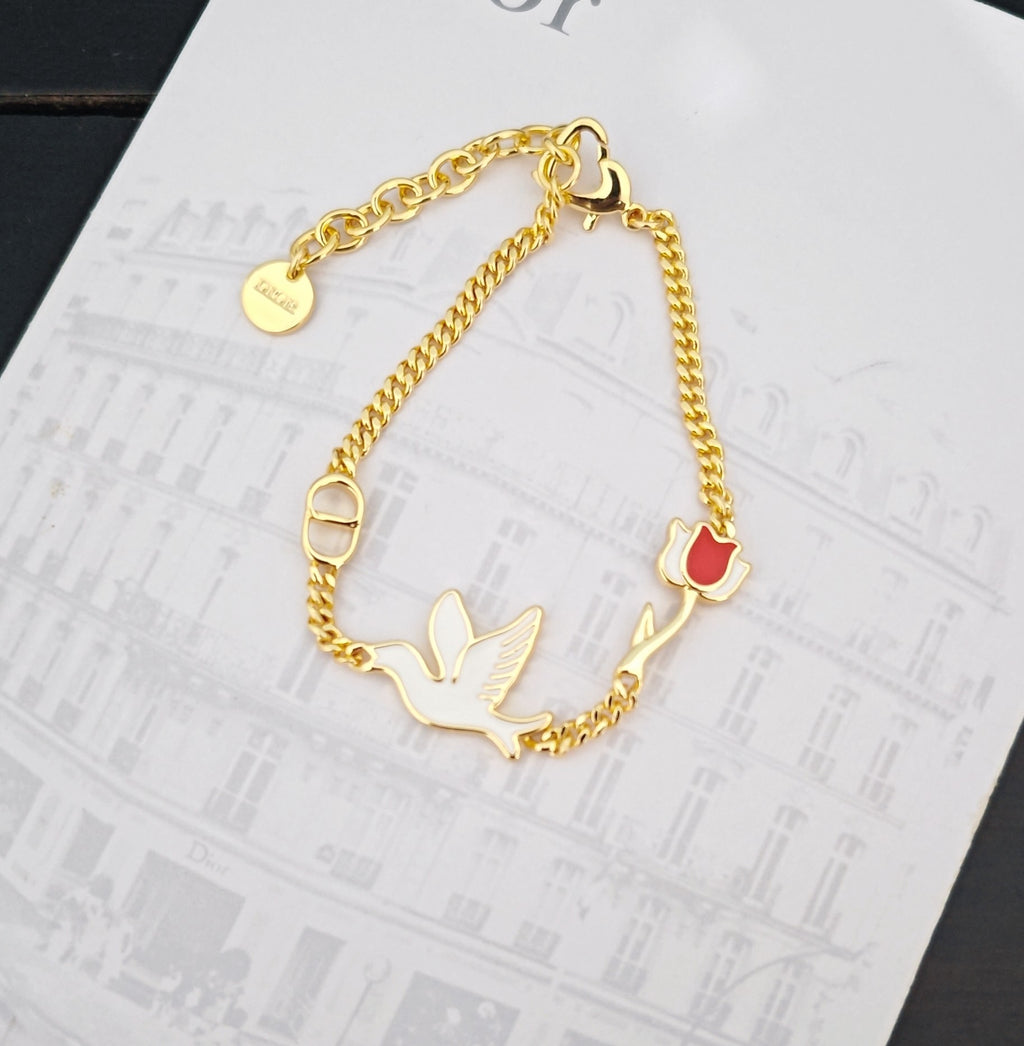Gold-tone bird charm bracelet with red enamel pendant and ring clasp