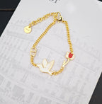 Gold-tone bird charm bracelet with red enamel pendant and ring clasp