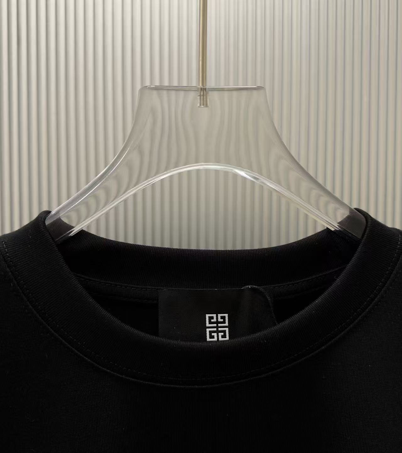 Black crew-neck T-shirt neckline detail with small logo label