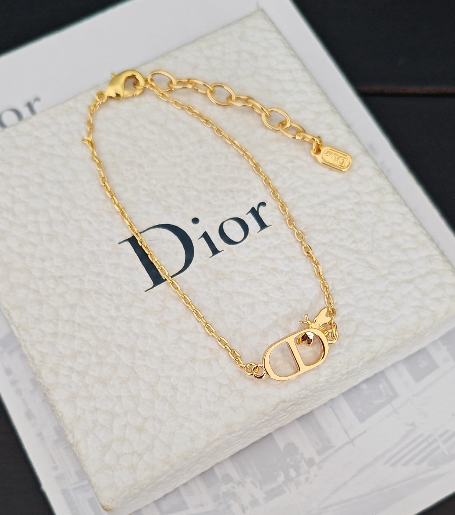 Gold-tone chain bracelet with Dior lettering and D charm on white box insert