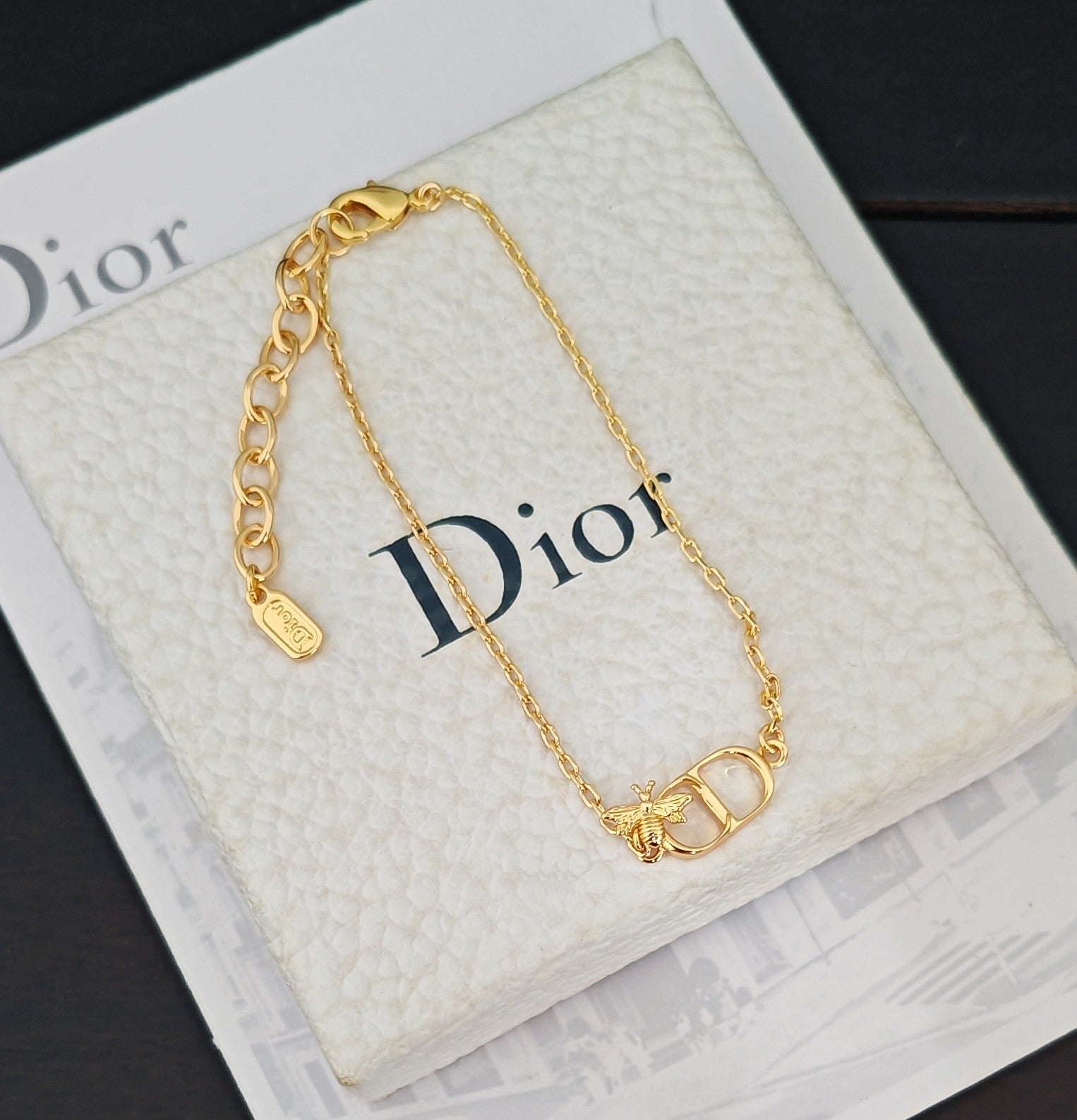 Gold-tone chain bracelet with Dior lettering and charm on white box insert