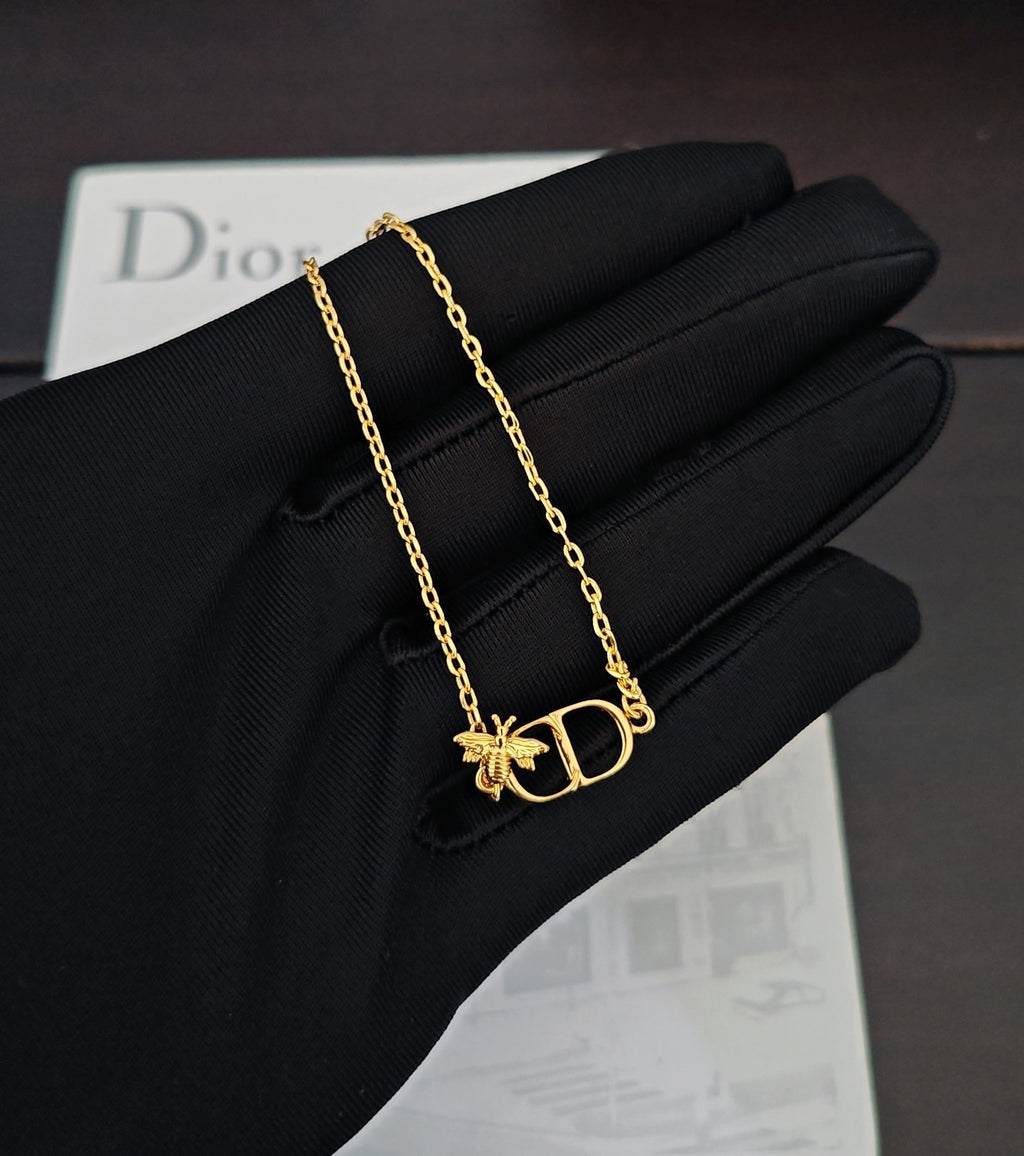 Gold-tone chain bracelet with Dior D pendant and butterfly charm on black glove