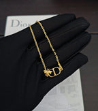 Gold-tone chain bracelet with Dior D pendant and butterfly charm on black glove