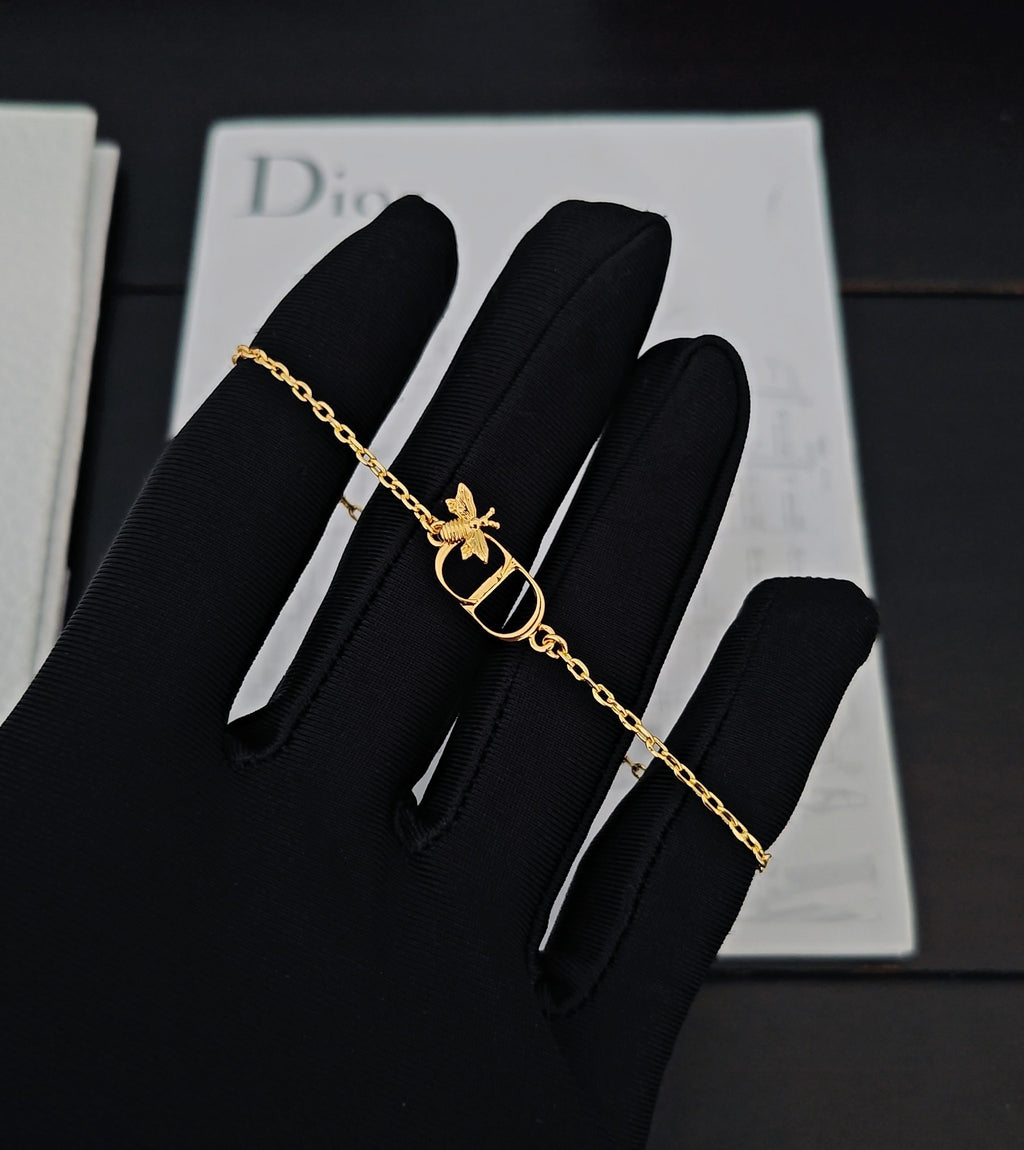 Gold-tone chain bracelet with butterfly charm and Dior D pendant on black glove