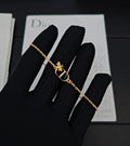 Gold-tone chain bracelet with butterfly charm and Dior D pendant on black glove