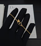 Gold-tone chain bracelet with butterfly charm and Dior D pendant on black glove