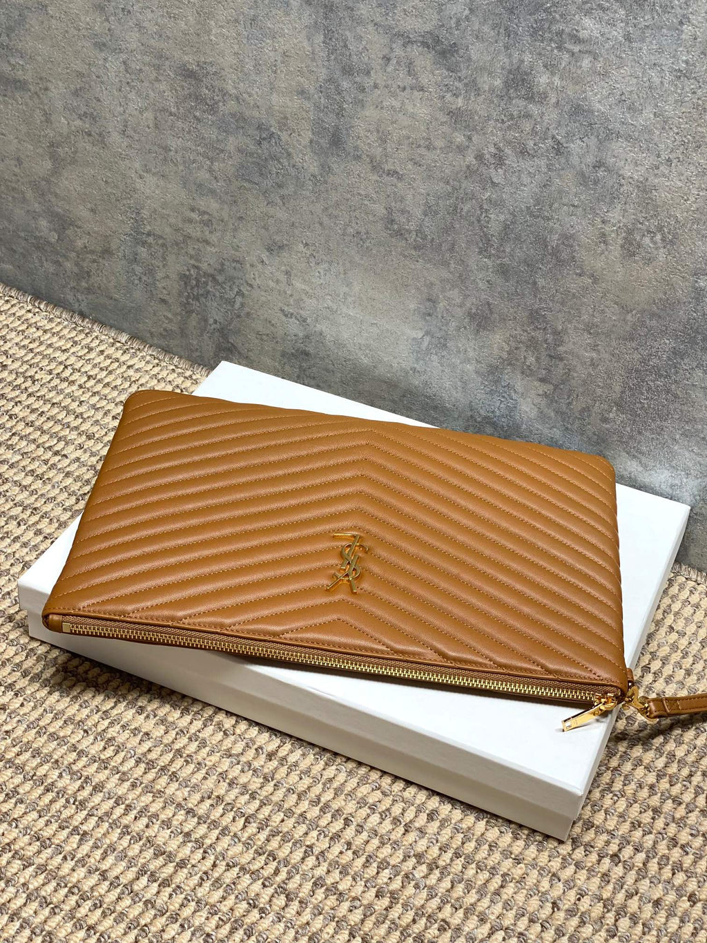 Tan quilted clutch bag with gold-tone zipper and YSL emblem at center