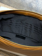 Tan clutch interior with dark lining, center label, and gold-tone zipper edge