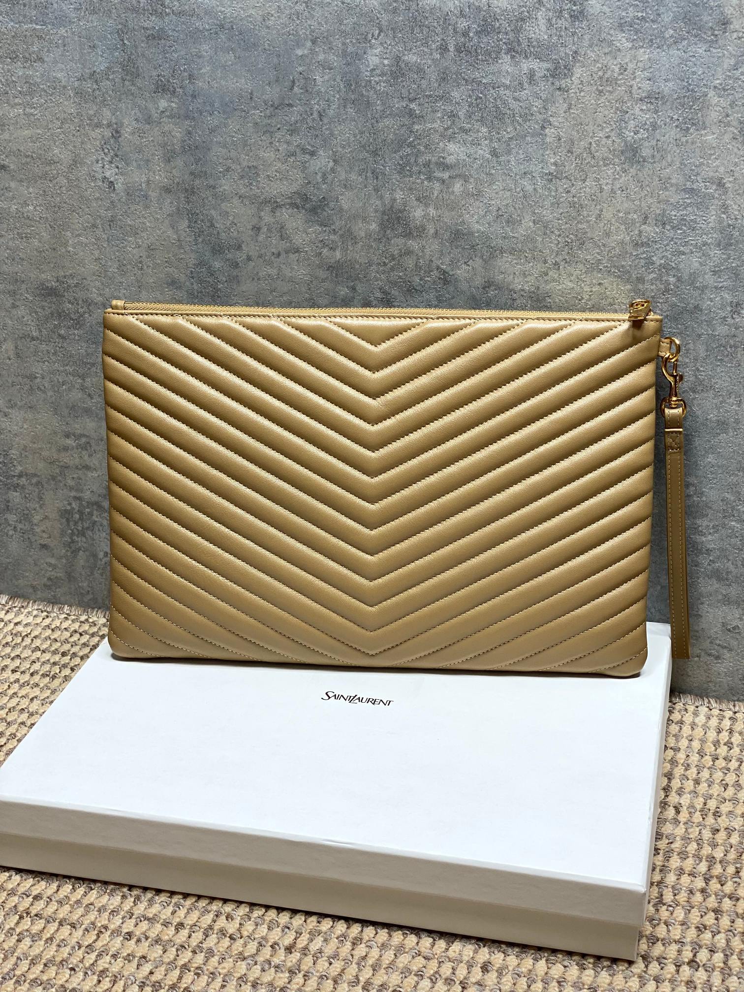 Gold quilted small bag with YSL logo, top zip and strap loops, chevron pattern.