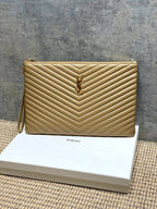Gold quilted small bag with YSL emblem and top zip, chevron pattern.
