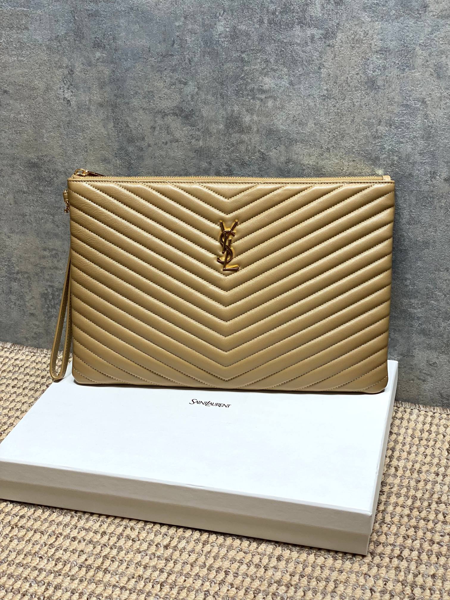 Gold quilted small bag with YSL emblem and top zip, chevron pattern.
