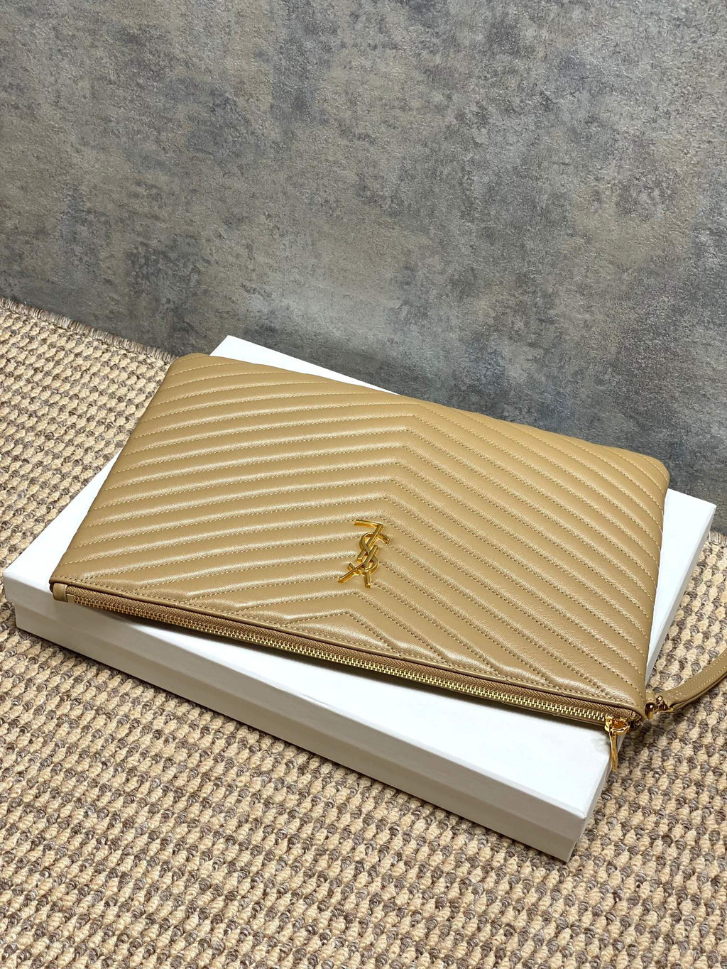 Gold quilted small bag with YSL logo and top zip; slim wrist strap visible.