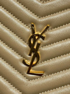 Gold YSL logo on chevron quilted leather small bag, close-up of emblem.