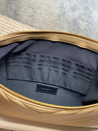 Dark fabric lining inside YSL small bag with stitched pocket and gold zipper edge.