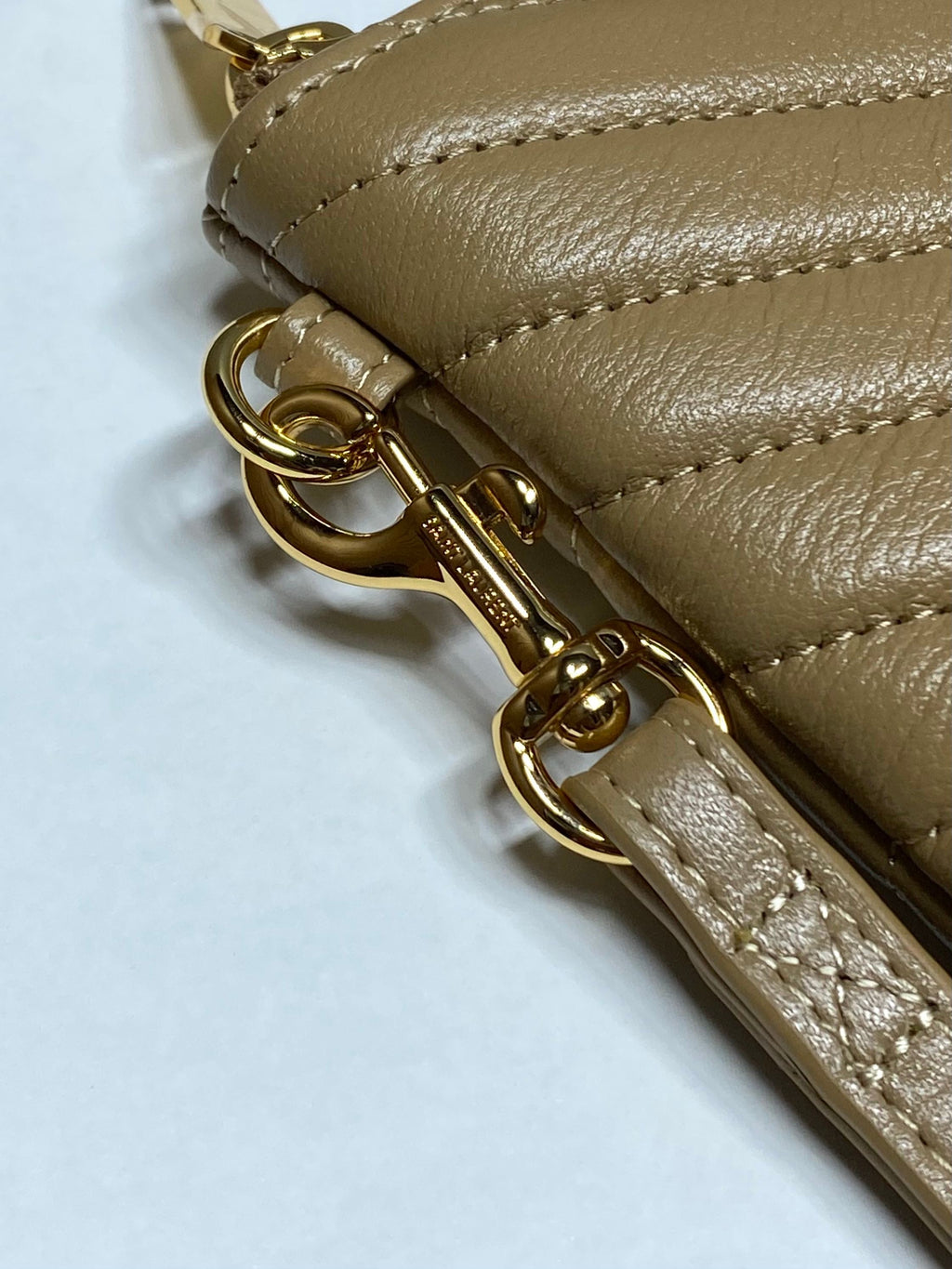 Gold zipper hardware and stitched edge on quilted leather YSL small bag, close-up.