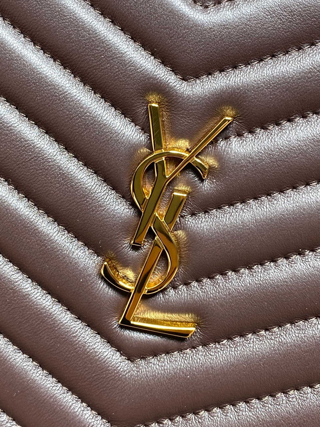 Gold YSL logo on dark brown quilted leather with chevron stitching