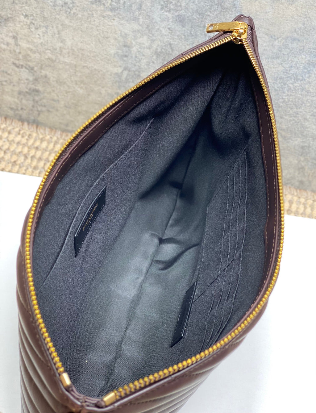 Dark fabric lining inside dark brown quilted bag with gold zipper edge