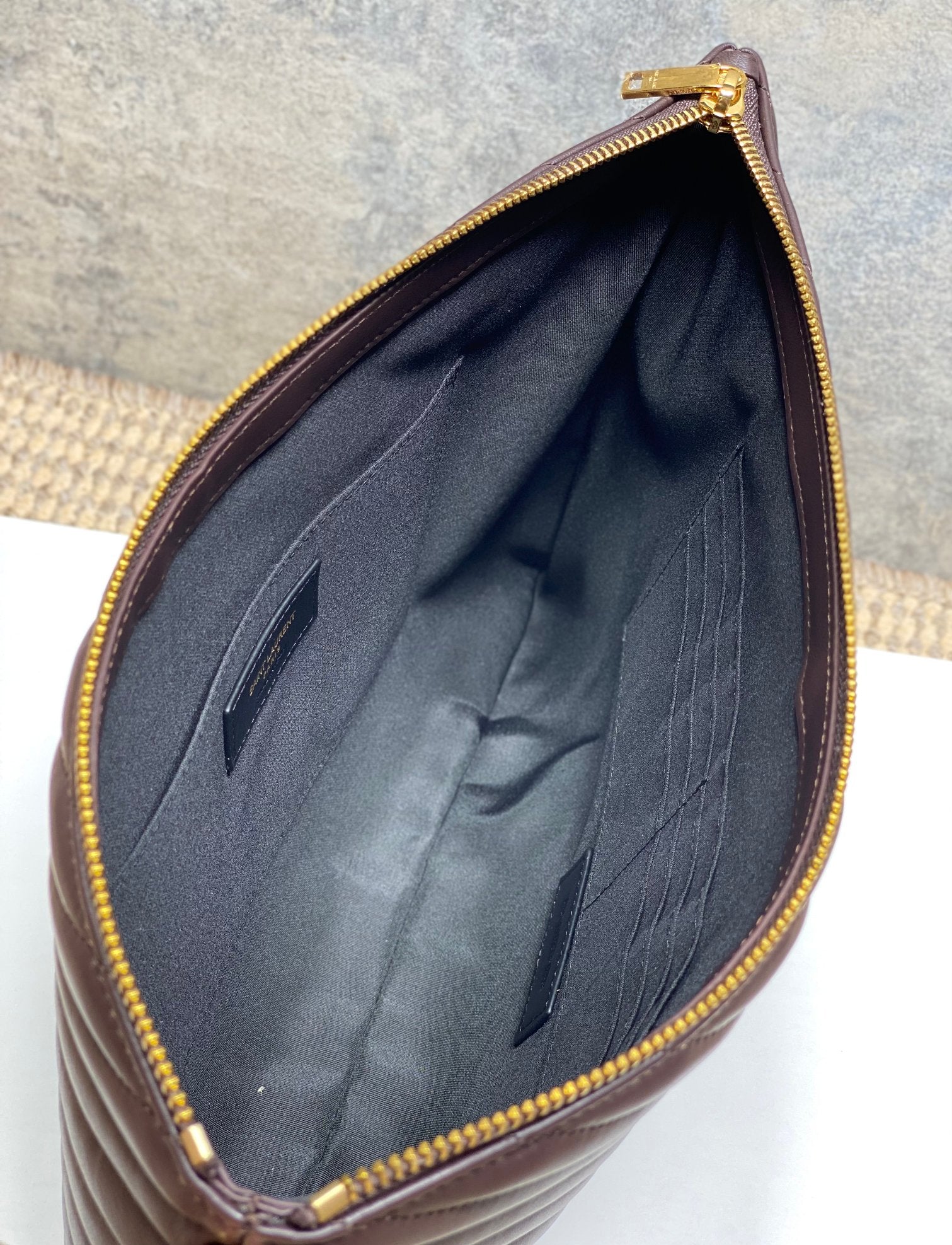 Dark fabric lining inside dark brown quilted bag with gold zipper edge