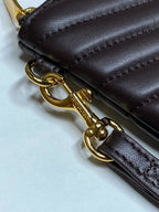 Gold chain clasp on dark brown leather bag with stitched edge