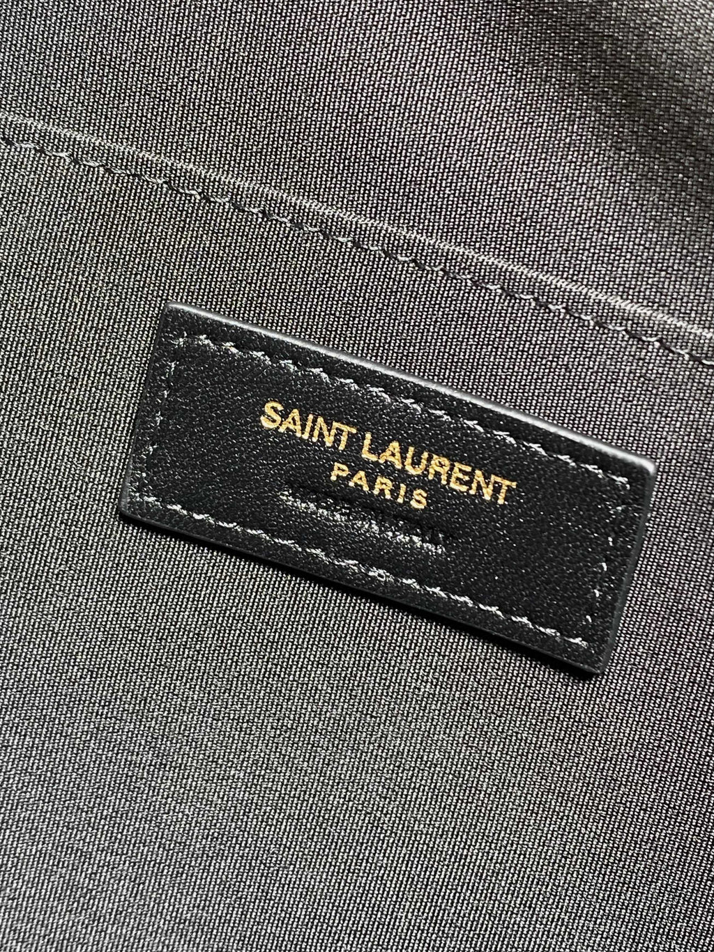 Saint Laurent Paris leather label on dark fabric lining inside the bag