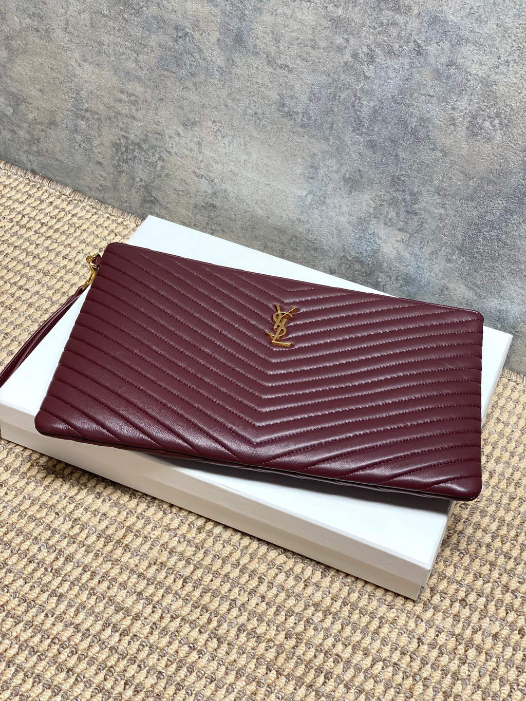 YSL burgundy quilted clutch with gold emblem and zip closure