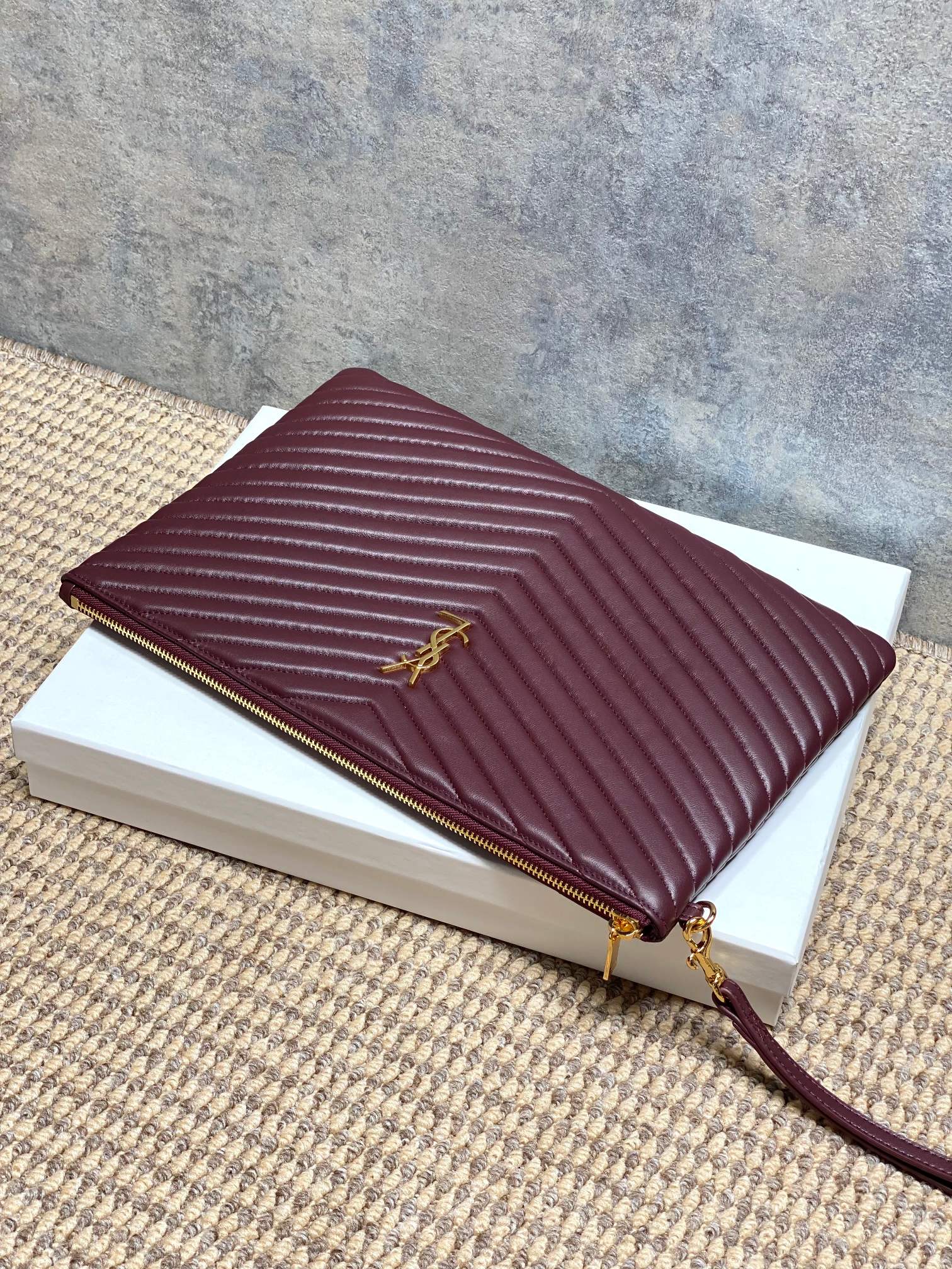 YSL burgundy quilted clutch with gold zip, wrist strap, and emblem