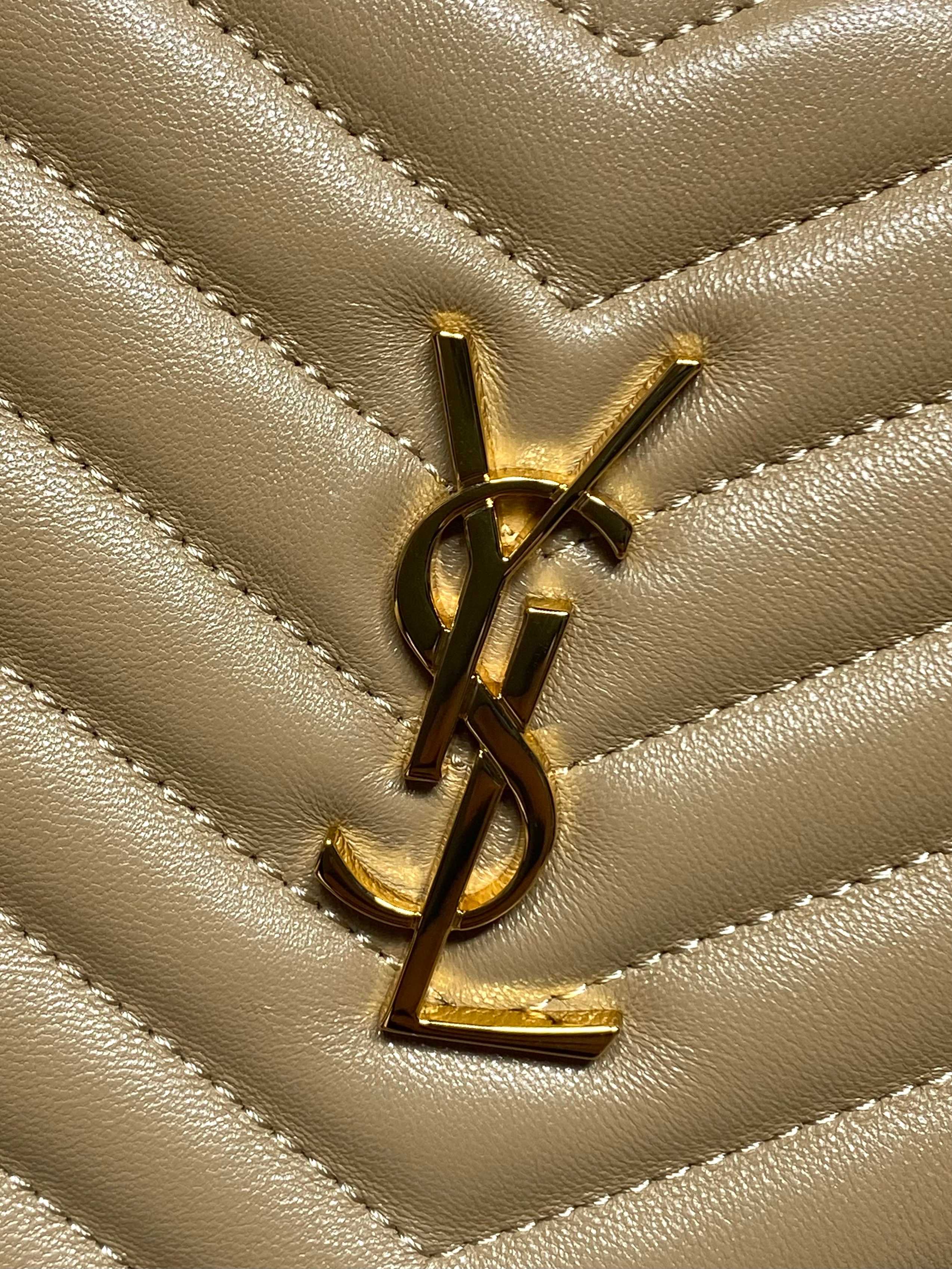 Gold YSL logo emblem on tan quilted leather with chevron stitching