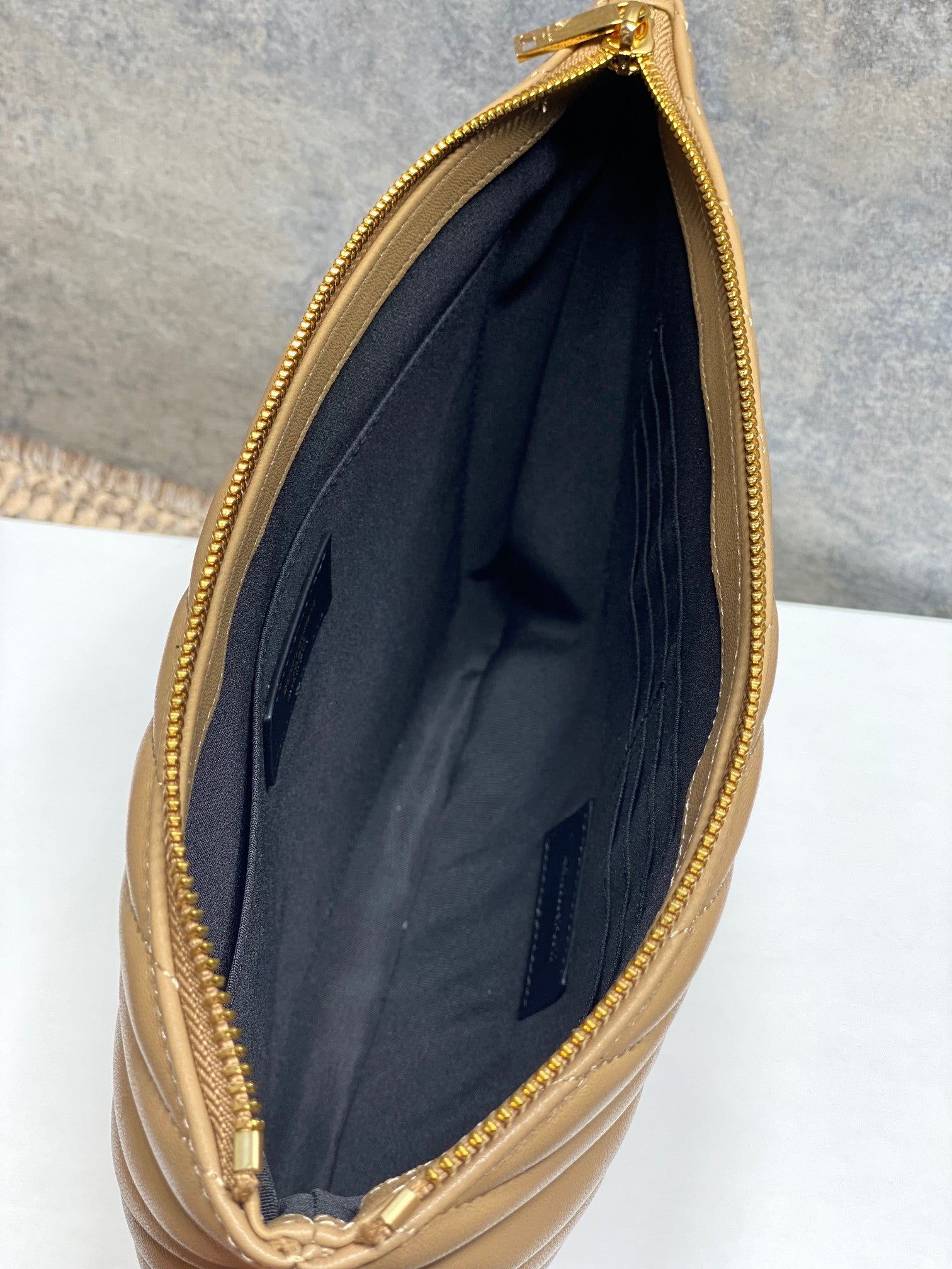 Open top of tan quilted small bag showing dark interior lining