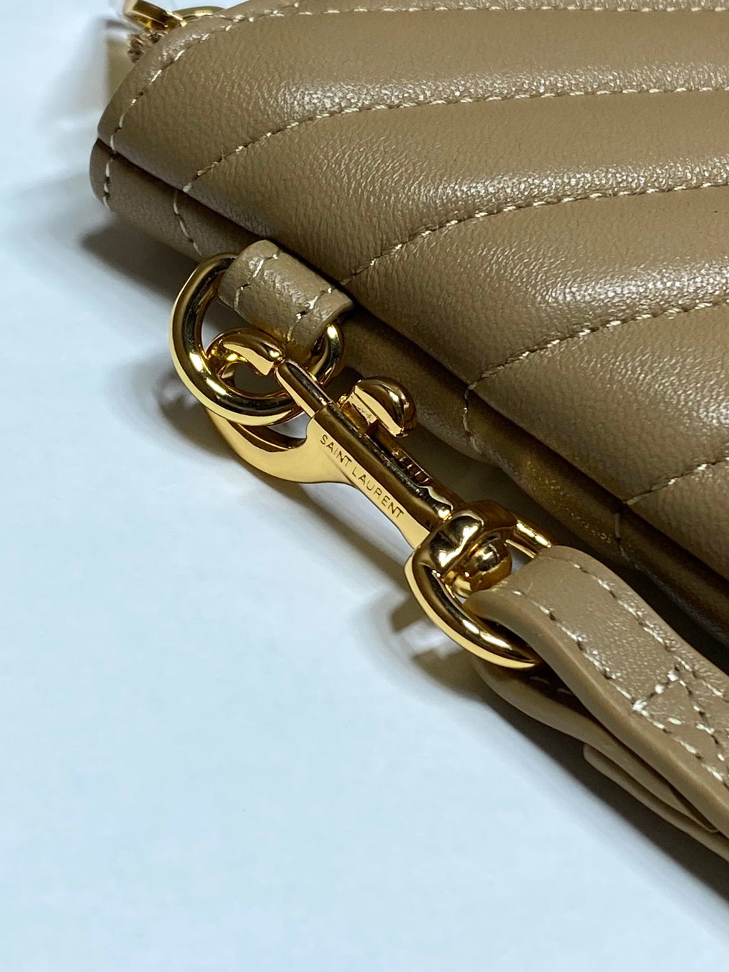 Gold zipper pull and hardware on tan quilted small bag